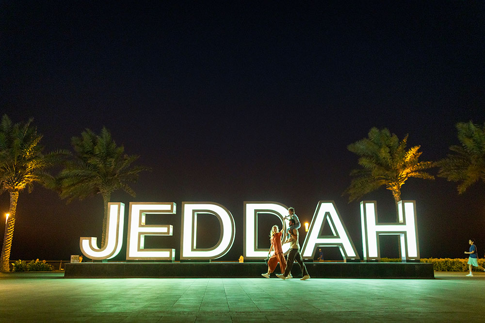 Family walking in front of Jeddah letters by the beach